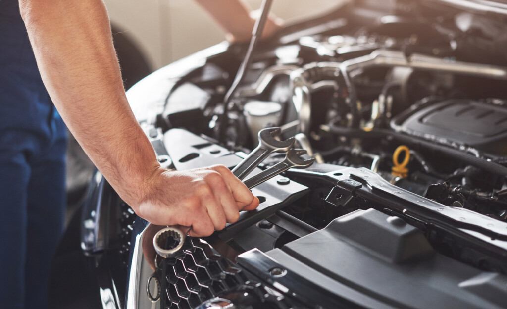 Muscular car service worker repairing vehicle